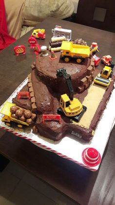 a birthday cake that is shaped like a construction site with trucks and tractors on it