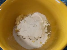 a yellow bowl filled with flour on top of a blue table