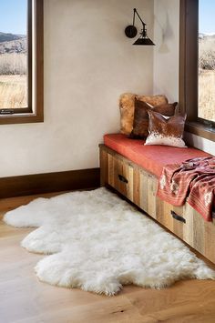 a white sheepskin rug sitting on top of a wooden bench next to a window