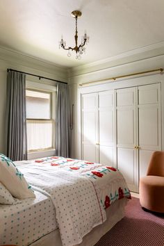 a bedroom with a bed, chair and closets in the corner by the window