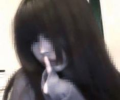 a blurry image of a woman with long hair making a hand gesture to the camera