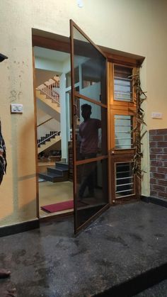 a man standing in an open door to a room that has stairs on the wall