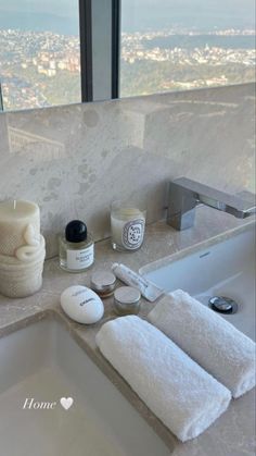 a bathroom sink with white towels and soaps on top of it next to a large window