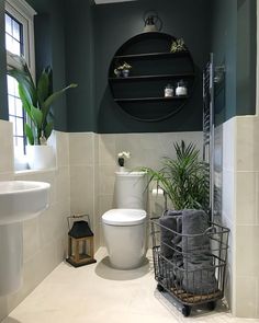 a white toilet sitting next to a bath tub under a window in a bathroom with green walls