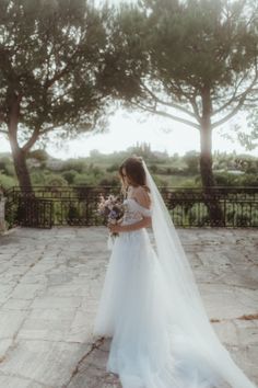 a woman in a wedding dress is standing outside