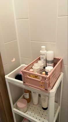 a bathroom shelf filled with cosmetics and personal care items on it's shelves in front of a white tiled wall