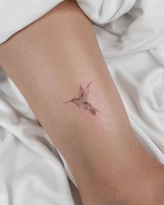 a small bird tattoo on the left arm and leg, with two birds flying above it