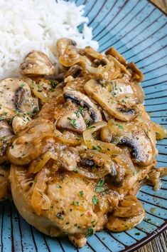 a blue plate topped with meat covered in mushrooms next to rice and broccoli