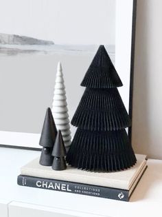 three black and white christmas trees sitting on top of a book next to each other