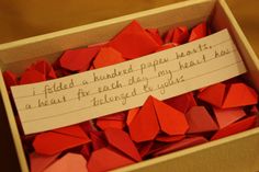 a box filled with red paper hearts next to a note that says i folded a hundred paper hearts