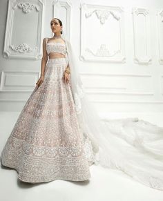 a woman in a wedding dress standing next to a white wall