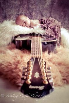 a baby sleeping on top of a guitar with the words tell me god written below it