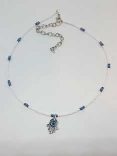 "Evil Eye Choker A fun trendy version of the ever popular Boho Choker, A Stunning whimsical white choker with focal Evil Eye charm. Choker made with 2/0 mm white colored glass seed beads, blue glass seed beads, pewter colored glass beads and quality jewelry findings. All beads are quality glass, and metal, purchased at exclusive bead shops. Choker measures 14\" with 3 inch extension chain. Jewelry items are secured with split rings to insure durability. This designer choker will look super nice White Bohemian Beaded Necklace With Evil Eye, Bohemian White Beaded Necklace With Evil Eye, Adjustable White Beaded Necklace With Evil Eye, White Evil Eye Beaded Bracelets For Festivals, White Evil Eye Jewelry For Festivals, Evil Eye Choker, Pretty Face Mask, White Choker, Choker Designs