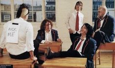 a group of people sitting around each other in front of desks with signs on them