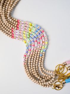 three strands of beaded necklaces with gold metal clasps and key rings on a white surface