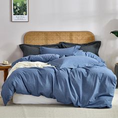 a bed with blue sheets and pillows in a bedroom next to a plant on the wall