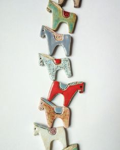 five ceramic horse brooches are arranged in a row on a white surface,