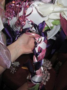 the bride's bouquet is wrapped in purple and white ribbon with pink flowers on it