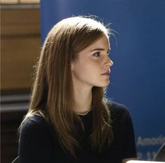 a woman sitting at a table in front of a blue sign that says naciones university