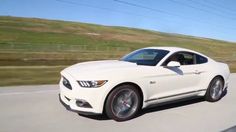 a white ford mustang driving down the road