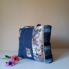 a denim purse with flowers on it and a flower in the corner next to it