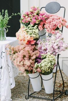 a bunch of flowers that are sitting on a stand in front of a white table