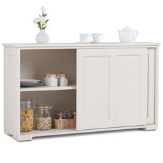 a white cabinet with two doors and some bowls on the bottom shelf next to it