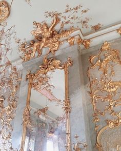 ornate gold mirrors and chandeliers in a room with white walls, gilded ceiling