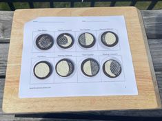 four different types of buttons sitting on top of a piece of white paper next to a wooden bench