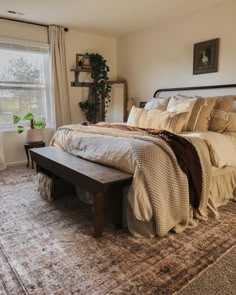 a bedroom with a large bed and a bench in front of the window that is open