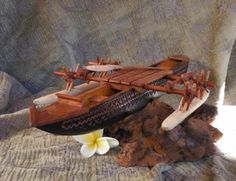 a wooden model of a boat with two paddles and a flower on the side