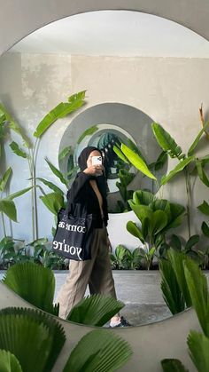 a person with a bag that says oma and you're in front of some plants