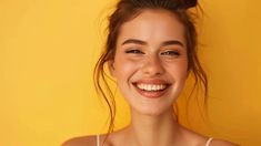 a young woman smiling and wearing a white tank top with her hair in a bun