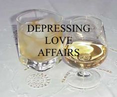 two glasses filled with white wine sitting on top of a table next to each other