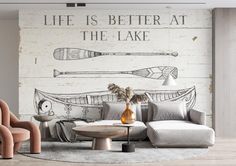 a living room with two chairs and a couch in front of a wall mural that says life is better at the lake