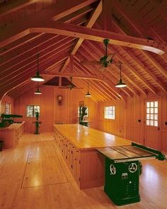 an empty room with wood floors and vaulted ceiling, large kitchen island in the center