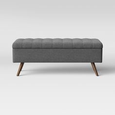 an upholstered bench with wooden legs and a buttoned seat on the back