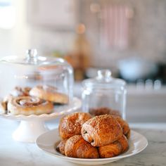 some pastries are sitting on a white plate next to a glass container with a lid