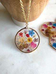 Oh wildflowers 🌸 is there anything better? This big circular pendant is made of real pressed flowers preserved into resin. There is gold leafing sprinkled into the resin to make the pendant really sparkle ✨This is made to last a long time and the high quality resin preserves the flowers to stay at this vibrancy for as long as the necklace lasts! The pendant is on a super long 28 inch chain with NO clasp. You can easily slip this over your head without having to mess with the closure in the back Bohemian Gold Flower Pendant Necklace, Gold Bohemian Flower Pendant Necklace, Gold Resin Nature-inspired Jewelry, Nature-inspired Gold Resin Jewelry, Multicolor Flower Jewelry With Pressed Flowers, Multicolor Flower Shaped Jewelry With Pressed Flowers, Bohemian Jewelry With Pressed Flowers In Resin, Gold Floral Resin Jewelry, Botanical Style Gold Resin Jewelry