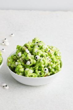 two bowls filled with green and white popcorn covered in googly eyes, sitting on a table