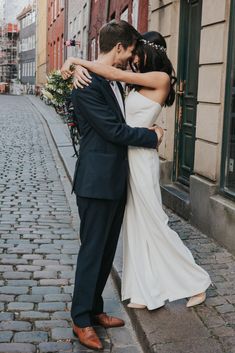 a bride and groom embracing on the street