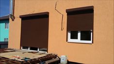 two brown roller up shades in front of a tan building with white trim on the windows