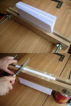 someone is using scissors to cut paper on a wooden table with other items around it