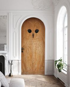 an owl door in the middle of a living room with white walls and wood floors