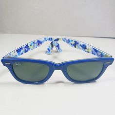 A vintage pair of blue/white Special Series floral motif RB2140 Wayfarer handmade unisex sunglasses from Ray Ban. . Brand: Ray Ban. . Model: RB2140 1019 50 22. . Series: Original Wayfarer Rare Prints. . Color: Blue, blue green and white floral patterns on the interior. . Lenses: Green, 100% UV Protection, G-15 Lens. . Hand made in Italy. Pre-owned, good condition. Few scratches on the original lenses and frame. Structurally and mechanically sturdy and sound. Please see photos. It comes in an aft Vintage Blue Sunglasses For Summer, Blue Vintage Sunglasses For Summer, Retro Blue Sunglasses For Spring, Retro Blue Polarized Sunglasses, Retro Blue Sunglasses With Polarized Lenses, Casual Blue Wayfarer Sunglasses, Retro Blue Wayfarer Sunglasses, Handmade Sunglasses, Unisex Sunglasses