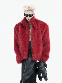 a woman in a red fur coat and black leather pants is holding a handbag