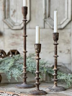 three candles sitting on top of a wooden table next to a wreath and other decorations