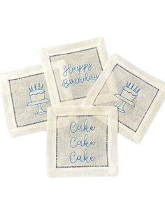 four embroidered napkins with the words happy birthday and cake in blue ink on them