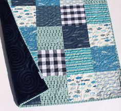 a quilted table runner with blue and white squares on the top, along with a black piece of fabric