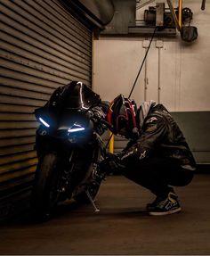 a man kneeling down next to a motorcycle with its headlight on and it's lights on